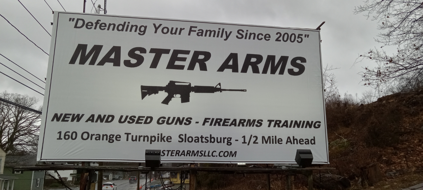 A large outdoor billboard advertises MASTER ARMS, offering new and used guns and firearms training. The sign also features a rifle image and states the location at 160 Orange Turnpike, Sloatsburg, 1/2 mile ahead.